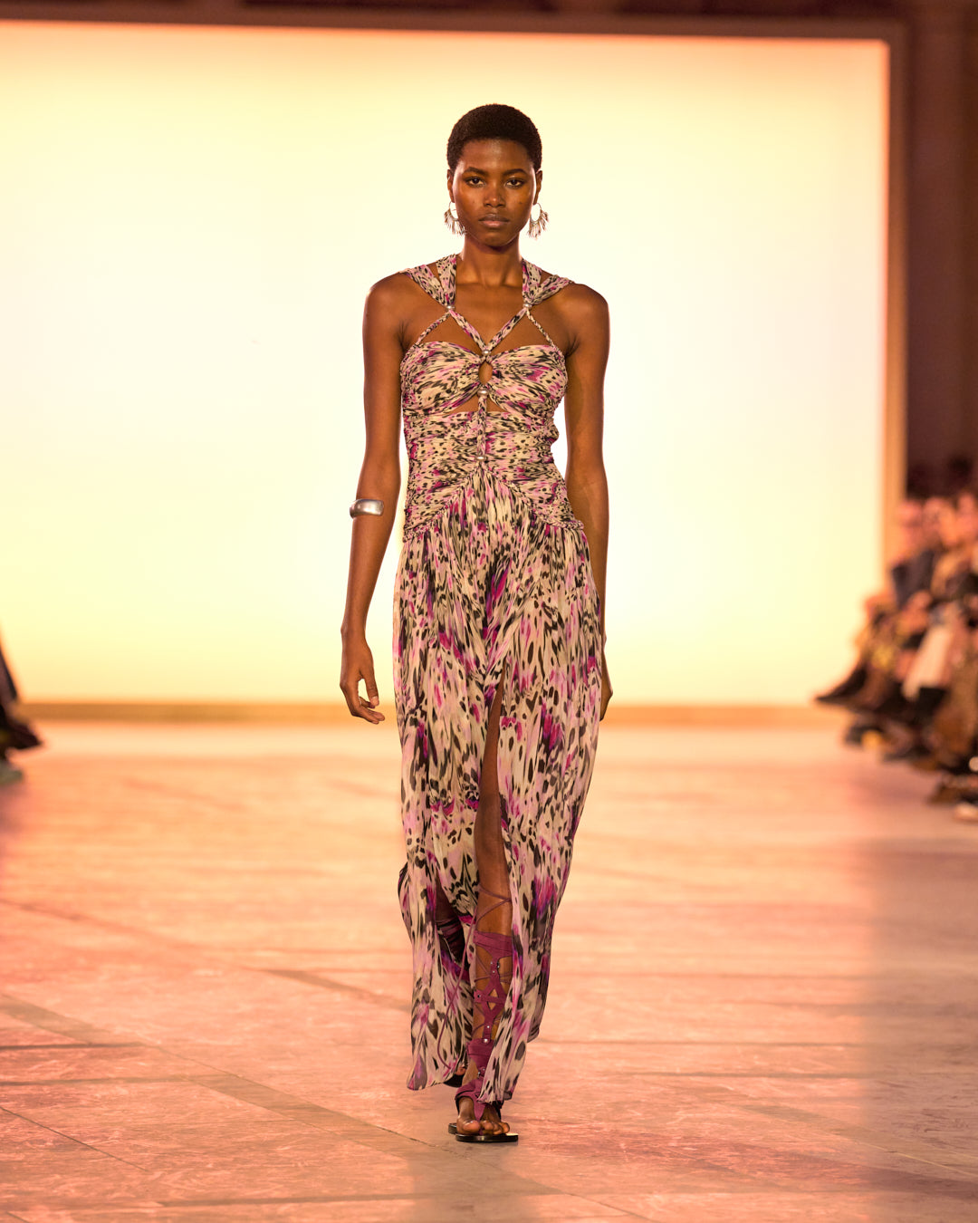 Female model on the catwalk, wearing the Rafael Strapless Dress in pink printed gathered silk and burgundy sandals.