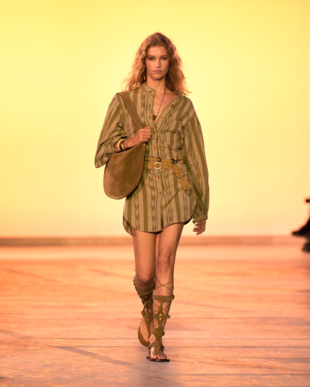 Female model on the catwalk, dressed in a striped shirt dress, camel sandals and the oskan hobo soft bag.